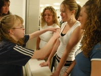 Several classmates talk with Alana, who holds court at the school store as part of a marketing class. Alana's aide looks on with some concern; Alana's words and actions can be unpredictable.   Dan Habib photo